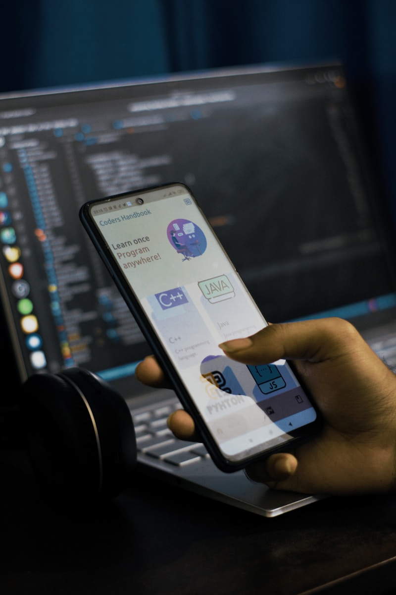 a person holding a cell phone in front of a laptop